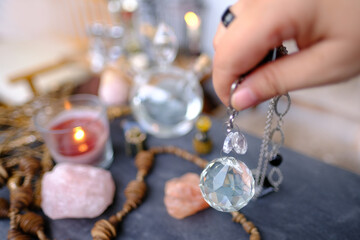 female hand with crystal glass ball, pendulum swings over astrologer's table, Harmony with...