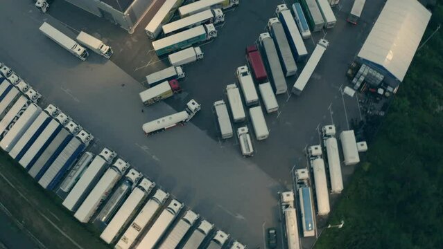 Tanker riding at warehouse depot with parked trucks aerial view. Lorry transporting cargo for delivery, driving to industrial building in evening tracking shot