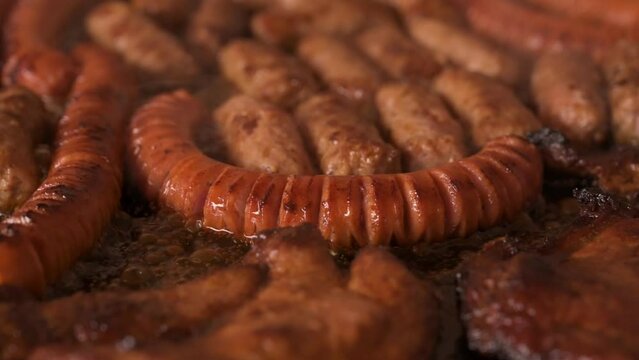 Closeup shot of cooking sausages, cevapi and chuck meat in lard - slow motion