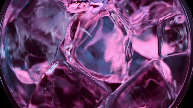 Super slow motion 1000fps top view on blue energy drink on red ice cubes in rotate glass.Slow motion turn red ice cubes and energy drink.Slow motion pours blue energy drink on ice cubes in turn glass