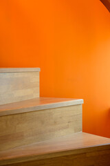 wooden stairs against an orange wall background, creating a visually striking contrast between natural and vibrant elements.
