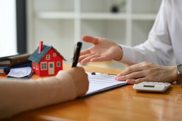 Fototapeta premium Financial advisor or realtor explaining contract details to clients at meeting. Mortgage, real estate and property concept