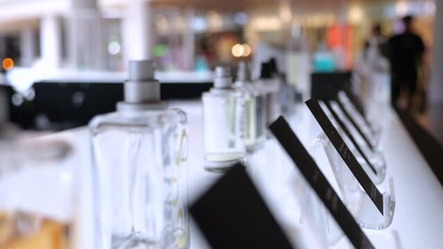 Close up of perfume in showcase, hand of woman buyer takes perfume bottle to inhale fragrance before buying, slow motion. Concept of cosmetics store, perfume shopping