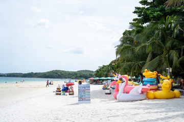 Fototapeta premium Image of tourists relaxing on weekends at white sandy beach with chairs, beach umbrellas and clear sky.