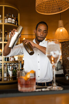 vertical photo of a latin bartender shaking the cocktail shakers