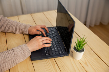Business woman working at laptop, no face. Hands of a female freelancer, working behind the table at home. Young woman working on laptop at home. Female hands typing on pc keyboard. Girl studying