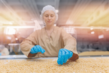 Worker woman for visual control quality raw pine nuts without shell on automatic conveyor belt for...