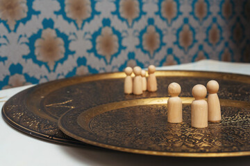 wooden figurines of people on the table. subject photo session of humanoid toys in the room. wooden toys on a bronze plate