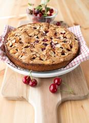 Cherry cake with almonds and sour cherries on light wooden table