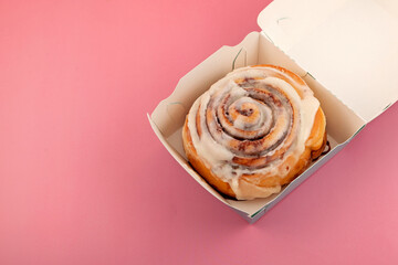 Cinnamon roll or cinnabon in paper box, top view. Homemade sweet traditional dessert buns with...