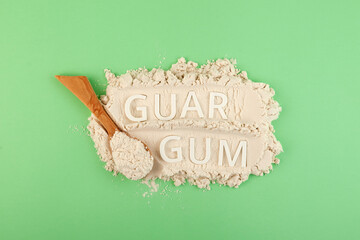 Guar gum powder or guarana in wooden spoon, top view. Inscription GUAR GUM. Design element. Food...