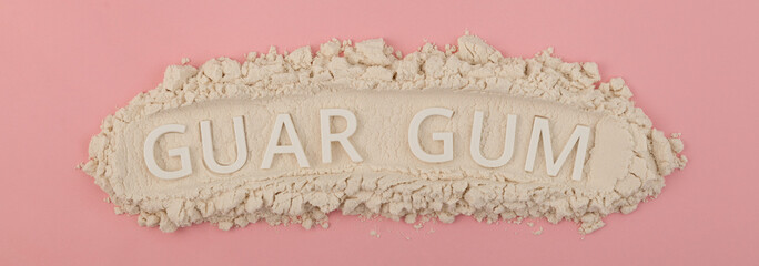 Food additive E412, banner, design element. Guar gum powder or guaran on  pink background....