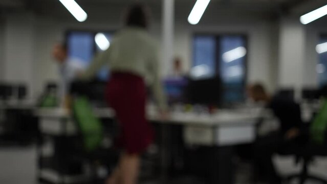Blurry video. Four colleagues finish work and get up from their desks. Slow motion. 