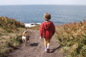 Niño pequeño paseando con su perro por la costa cerca del mar