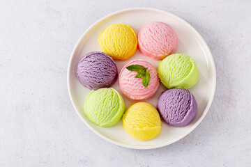Pastel colored ice cream scoops on white plate, top view.