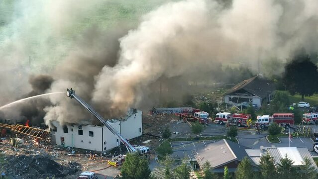 Aftermath of the explosion due to propane leakage, Fire and massive smoke in the air, Firefighting trucks and engines at the explosion site, Aerial View