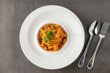 Shrimp spaghetti on white porcelain plate on black stone table