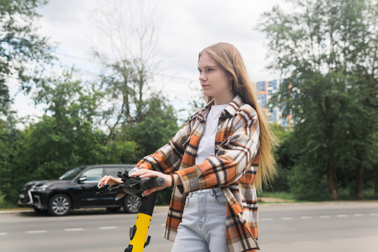 young woman on an electric scooter rides down the street