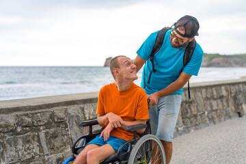 Disabled person in a wheelchair being pushed by a friend on the beach promenade, having fun in summer