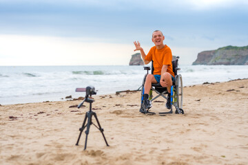 Portrait of a disabled person in a wheelchair on the beach recording a video blog