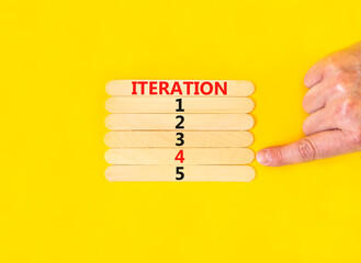 Time to iteration 4 symbol. Concept word Iteration 1 2 3 4 5 on wooden sticks. Businessman hand. Beautiful yellow table yellow background. Business planning and time to iteration 4 concept. Copy space