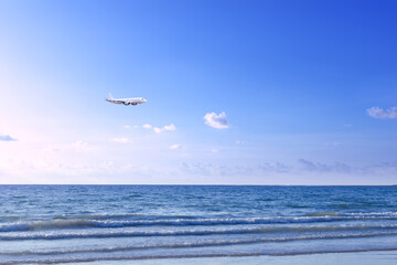 Commercial airplane above sea in summer season and clear blue sky over beautiful scenery sandy beach background, Concept business travel and transportation summer vacation travel.