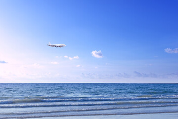 Naklejka na ściany i meble Commercial airplane above sea in summer season and clear blue sky over beautiful scenery sandy beach background, Concept business travel and transportation summer vacation travel.