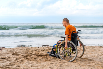 Portrait a disabled person in a wheelchair on the beach pensive by the sea