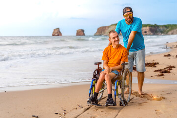 A disabled person in a wheelchair on the beach pushed by a friends by the sea
