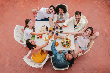 High angle top view of a group of best friends toasting wine glasses smiling and looking up to the...