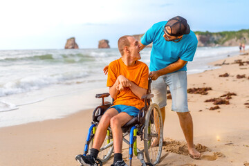 A disabled person in a wheelchair on the beach pushed by a friends by the sea, enjoying the summer