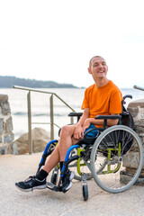 Portrait of pretty cheerful disabled person in wheelchair at the beach on summer vacation smiling
