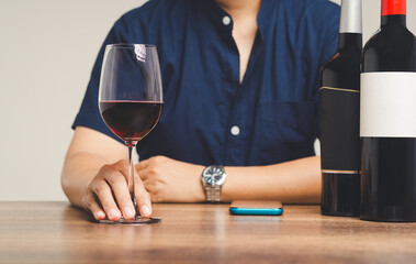 A businessman's right hand touches the base of a glass of red wine at the table.