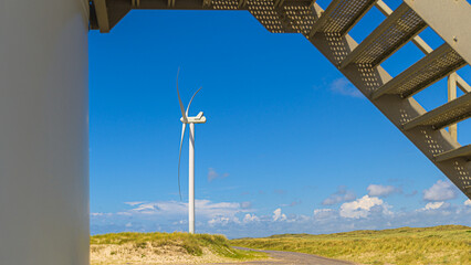 Windrad steht an der Küste in den Dünen am Strand und erzeugt alternative Energie durch Wind