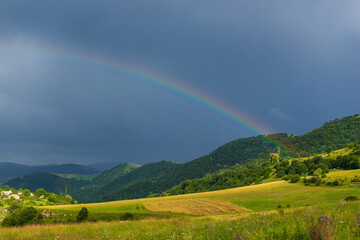 Rural landscape with clouds and rainbow