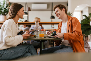 Cheerful couple having lunch together while sitting in cafe - 622256151