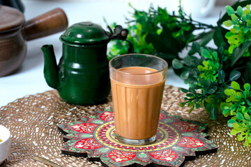 Fresh milk tea or indian karak chai in glass with chanak or masala tea in glass cup on textured background