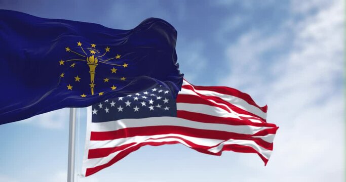 Indiana state flag waving with the national flag of the United states on a clear day