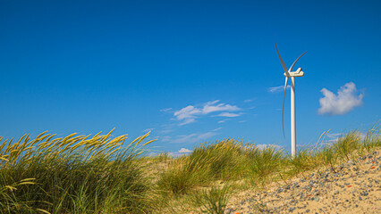Windrad steht an der Küste in den Dünen am Strand und erzeugt alternative Energie durch Wind