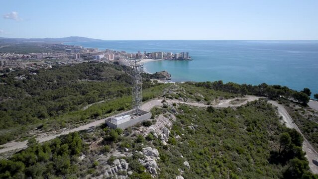 4K drone view flight next to a spinning maritime radar on top of the hill towards the blue Mediterranean Sea in Oropesa del Mar, Castellon, Spain