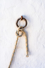 Closeup of a rope hanging from a ring with a beautiful knot. Village of Folegandros Island. Cyclades of Greece.