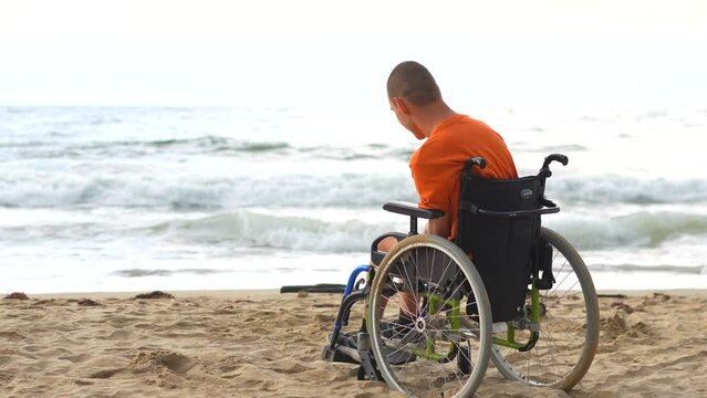 Portrait a disabled person in a wheelchair on the beach pensive by the sea