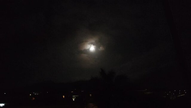 Moon partially covered by clouds on a summer night in a town in the north of Tenerife