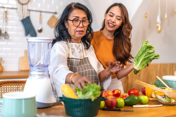 Portrait of happy love asian family senior mature mother and young daughter smiling cooking vegan...