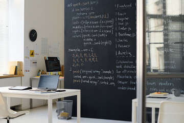 Modern empty IT class with formulas on blackboard and codes on computers