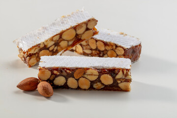 Turrón de Almendras con caramelo  sobre fondo blanco, Navidad. Almond nougat with caramel on a white background, Christmas.
