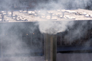 Close-up of smoking tin pipes against the background of industrial premises, houses