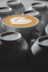 Bright photo for coffeeshop stories advertising. Logo heart on alone coffee latte or cappuccino in white cup background, top view