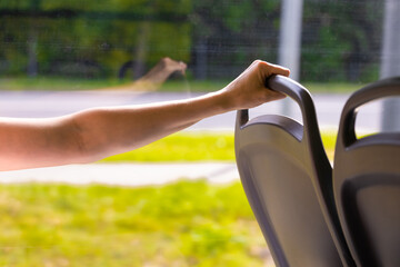 woman on the bus holding the handle on the chair.