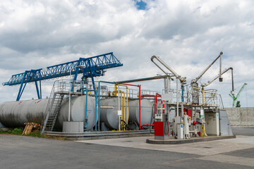 Large industrial filling station with big fuel tanks and overhead crane.